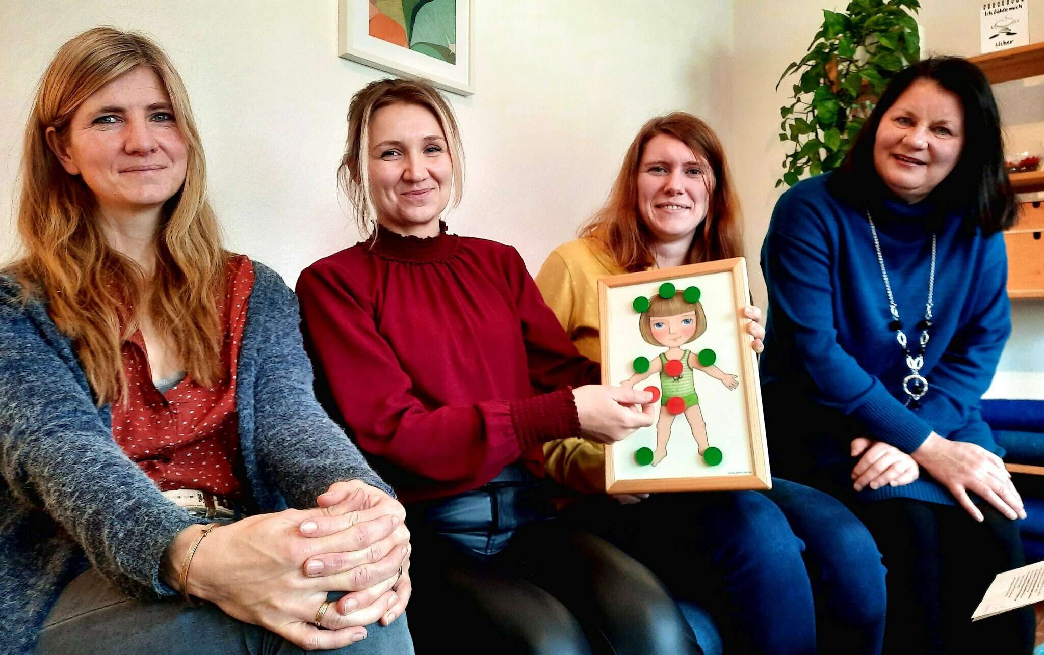 Anika Neubauer (l.), Klaudia Kisselt, Katja Mevenkamp und Angela Hesse mit einer Zeichnung, auf der Kinder mit roten Magneten zeigen können, an welchen Stellen ihres Körpers sie nicht angefasst werden möchten. 