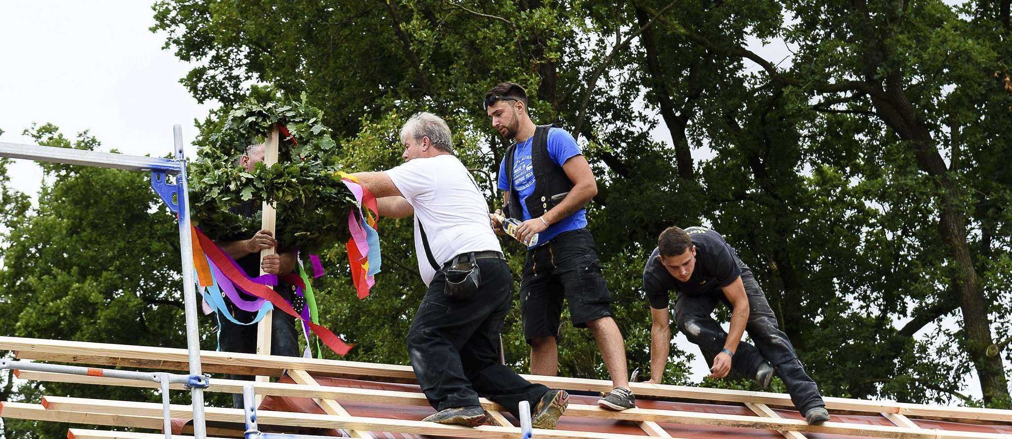 Helfer machen den Richtkranz auf dem Dach des neuen Krippenanbaus fest. Foto: Klaus-Dieter Plage